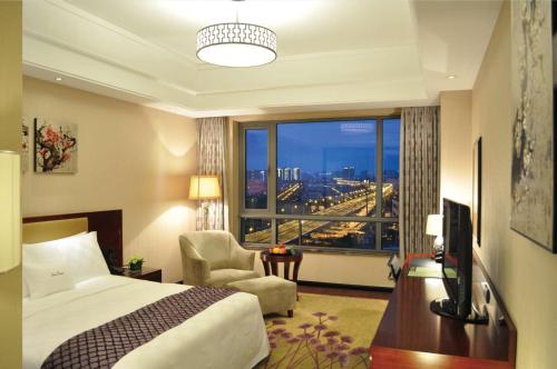 a hotel room with a bed and a desk and a window at DoubleTree By Hilton Wuxi in Wuxi