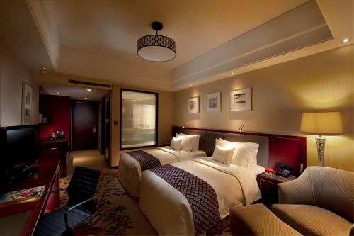 a hotel room with two beds and a couch at DoubleTree By Hilton Wuxi in Wuxi
