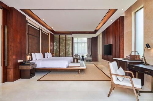 Schlafzimmer mit einem Bett, einem Schreibtisch und einem TV in der Unterkunft Lushan West Sea Resort, Curio Collection by Hilton in Jiujiang