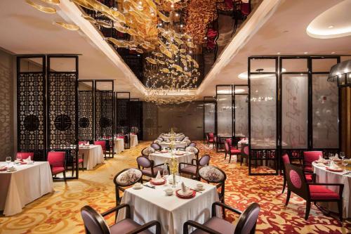 a dining room with tables and chairs and a chandelier at Hilton Yantai in Yantai