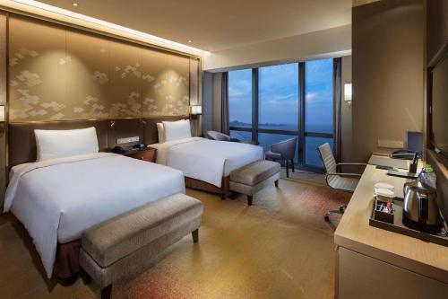 a hotel room with two beds and a large window at Hilton Yantai in Yantai