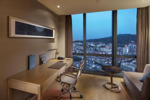 an office with a desk with a view of a city at Hilton Yantai in Yantai