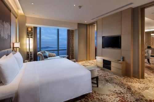 a bedroom with a large white bed and a television at Hilton Yantai in Yantai