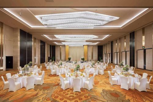 a large banquet hall with white tables and white chairs at Hilton Yantai in Yantai