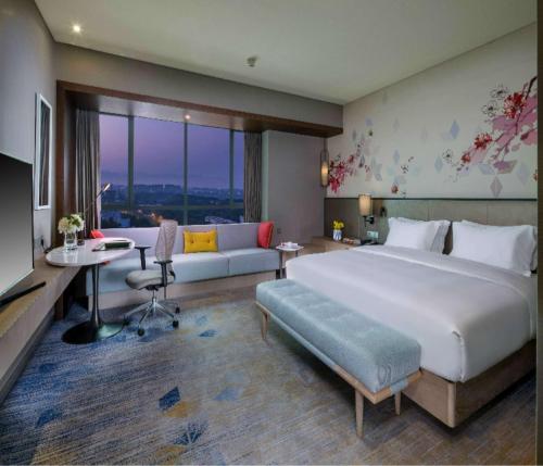 a bedroom with a large bed and a living room at Hilton Garden Inn Zhongshan Guzhen in Zhongshan