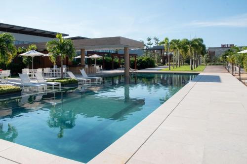 a swimming pool with white chairs and umbrellas at île de Pipa - Ma Plage Hotel in Pipa