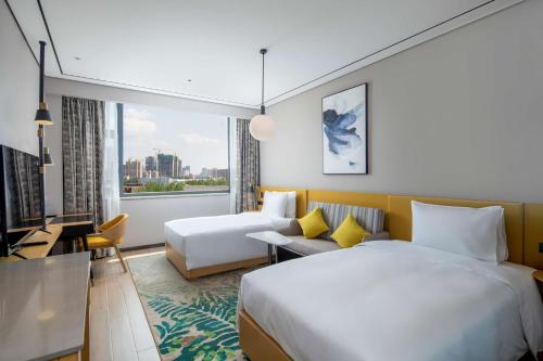um quarto de hotel com duas camas e um sofá em Hilton Garden Inn Changchun Economic Development Zone em Changchun