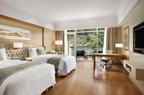 a hotel room with two beds and a desk at Hilton Hangzhou Qiandao Lake Resort in Thousand Island Lake