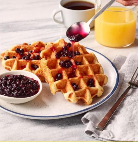 two waffles on a plate with a spoon and syrup at Fairfield Inn & Suites by Marriott Waco North in Waco