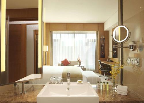 a bathroom with a sink and a bed and a mirror at DoubleTree By Hilton Jiaxing in Jiaxing