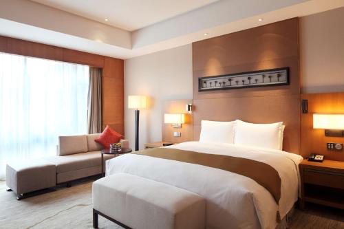 a hotel room with a large bed and a chair at DoubleTree By Hilton Jiaxing in Jiaxing