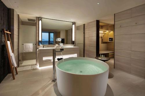 a bathroom with a bath tub and a sink at Doubletree Resort By Hilton Hainan - Xinglong Lakeside in Wanning