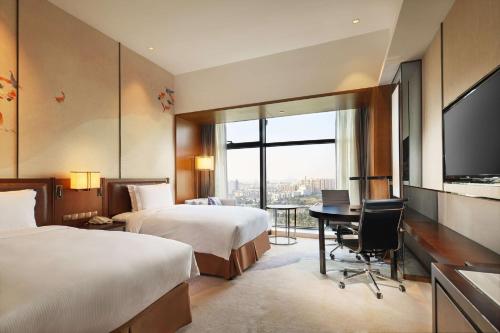a hotel room with two beds and a desk and a television at DoubleTree By Hilton Ningbo Beilun in Ningbo