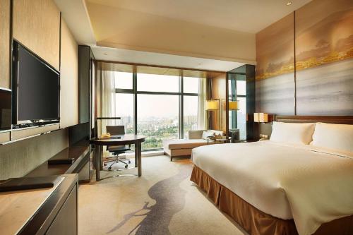 a bedroom with a bed and a tv and a desk at DoubleTree By Hilton Ningbo Beilun in Ningbo