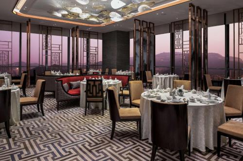 a dining room with tables and chairs and windows at Hilton Jinan South Hotel & Residences in Jinan