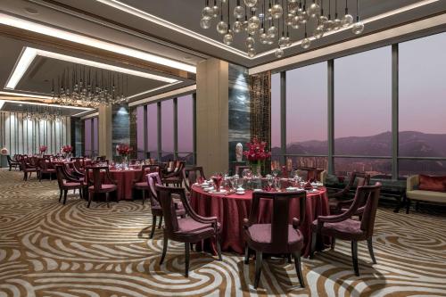a dining room with tables and chairs and large windows at Hilton Jinan South Hotel & Residences in Jinan