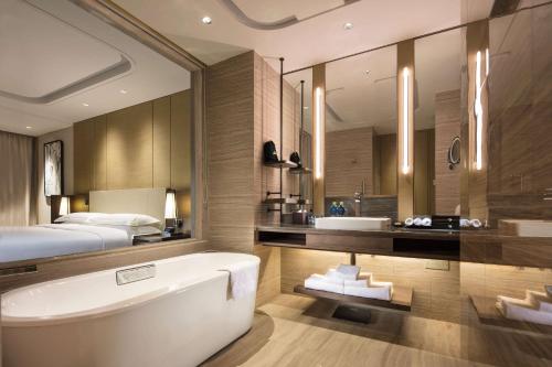a bathroom with a bed and a bath tub and a sink at Hilton Jinan South Hotel & Residences in Jinan