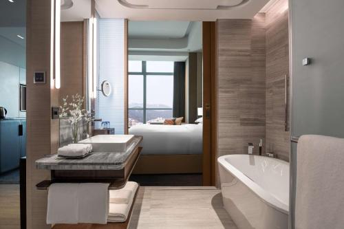 a bathroom with a tub sink and a bed at Hilton Jinan South Hotel & Residences in Jinan