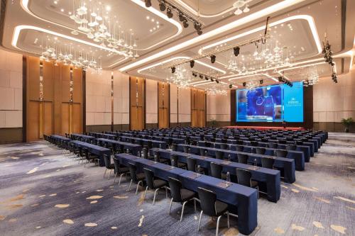 a large room with rows of chairs and a screen at Hilton Jinan South Hotel & Residences in Jinan