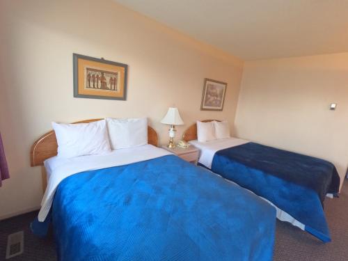 two beds in a hotel room with blue sheets at Westview Motel in Vegreville