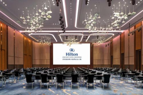 a hall with tables and chairs and a screen at Hilton Jinan South Hotel & Residences in Jinan