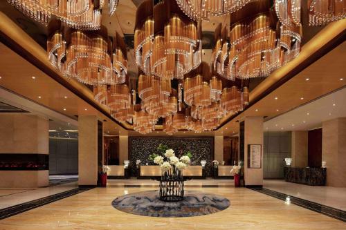 a lobby with chandeliers and flowers in a room at Hilton Zhengzhou in Zhengzhou