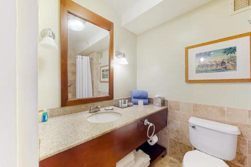 a bathroom with a toilet and a sink and a mirror at Condos in Kauai Beach Resort in Hanamaulu