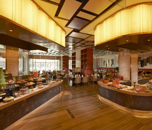 a restaurant with a buffet line with tables and chairs at Hilton Zhengzhou in Zhengzhou