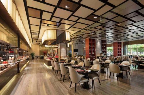 una sala da pranzo con tavoli e sedie in un ristorante di Hilton Zhengzhou a Zhengzhou