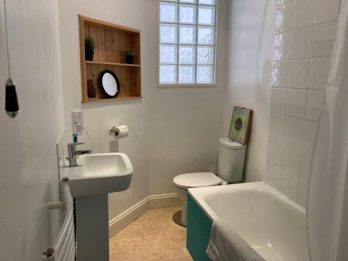 baño con lavabo y aseo y ventana en The Vineyard (Home of the think pod) en Portsmouth