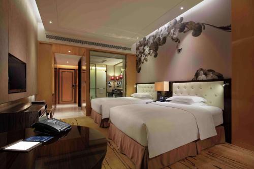 a hotel room with two beds and a television at Hilton Zhengzhou in Zhengzhou