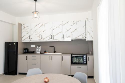 una cucina con armadi bianchi, tavolo e frigorifero nero di Ennea Suites-Flame suite a Flámbouras