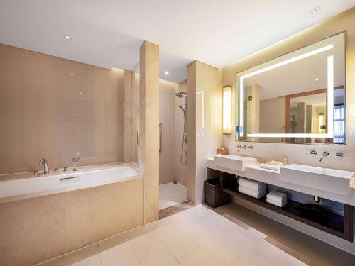 a bathroom with two sinks and a tub and a mirror at Hilton Garden Inn Chengdu Huayang in Chengdu
