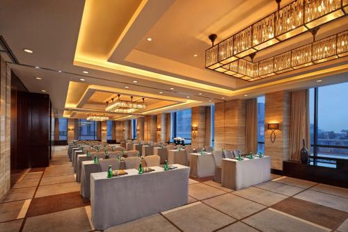 un restaurante con mesas y sillas blancas y ventanas en Hilton Beijing Wangfujing, en Beijing