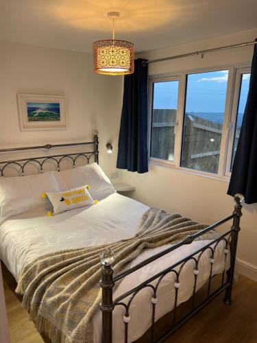 a bedroom with a bed with a chandelier and two windows at Citrus Chalet in Redruth