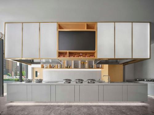 a kitchen with white cabinets and a flat screen tv at Hilton Garden Inn Tianjin Huayuan in Tianjin