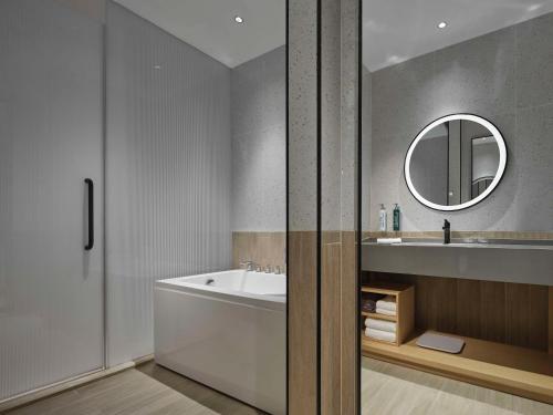 a bathroom with a tub and a sink and a mirror at Hilton Garden Inn Tianjin Huayuan in Tianjin