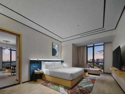 a hotel room with a bed and a tv at Hilton Garden Inn Tianjin Huayuan in Tianjin