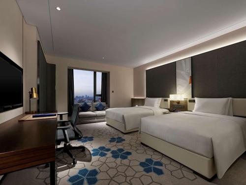 a hotel room with two beds and a desk at Doubletree By Hilton Baoding in Baoding