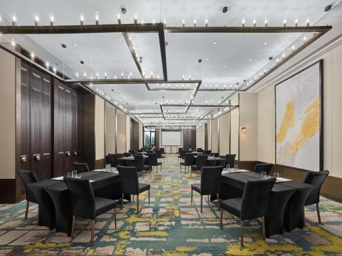 a conference room with tables and chairs and a projection screen at Doubletree By Hilton Baoding in Baoding
