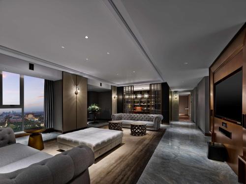 Doubletree By Hilton Baoding في Baoding: غرفة معيشة مع أريكة وتلفزيون