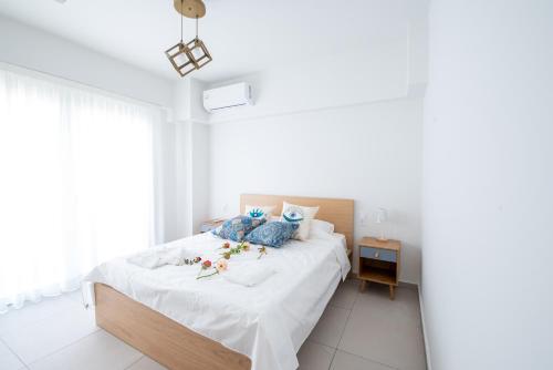 una camera da letto con un letto con lenzuola bianche e cuscini blu di Ennea Suites-Flame suite a Flámbouras