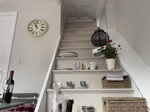 a stairway with a clock on the wall and a shelf at The Greig 2 in Wadhurst
