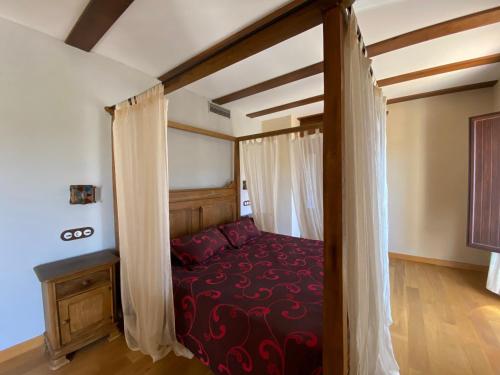 a bedroom with a canopy bed with a red blanket at Hotel Rural Centro de las Arribes in Aldeadávila de la Ribera