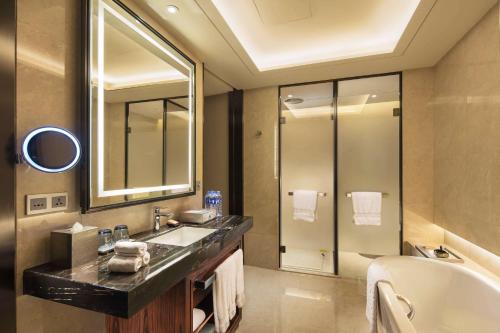 a bathroom with a sink and a tub and a mirror at DoubleTree by Hilton Hotel Anshun in Anshun