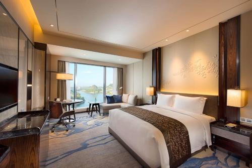 a bedroom with a large bed and a living room at DoubleTree by Hilton Hotel Anshun in Anshun