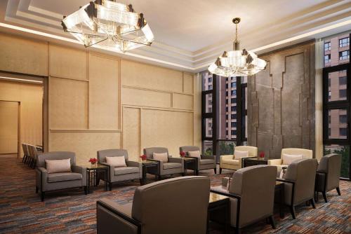 a waiting room with chairs and tables and chandeliers at Conrad Tianjin in Tianjin
