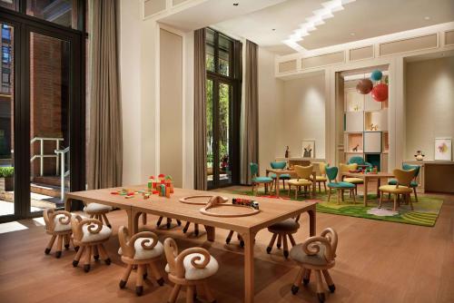 a dining room with a table and chairs and a room with windows at Conrad Tianjin in Tianjin