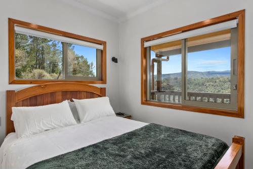 a bedroom with a bed and two windows at Remutaka retreat in Upper Hutt