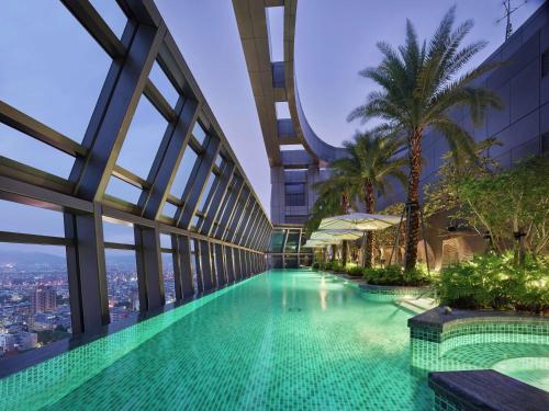 台北的住宿－台北新板希爾頓酒店，棕榈树建筑中间的游泳池